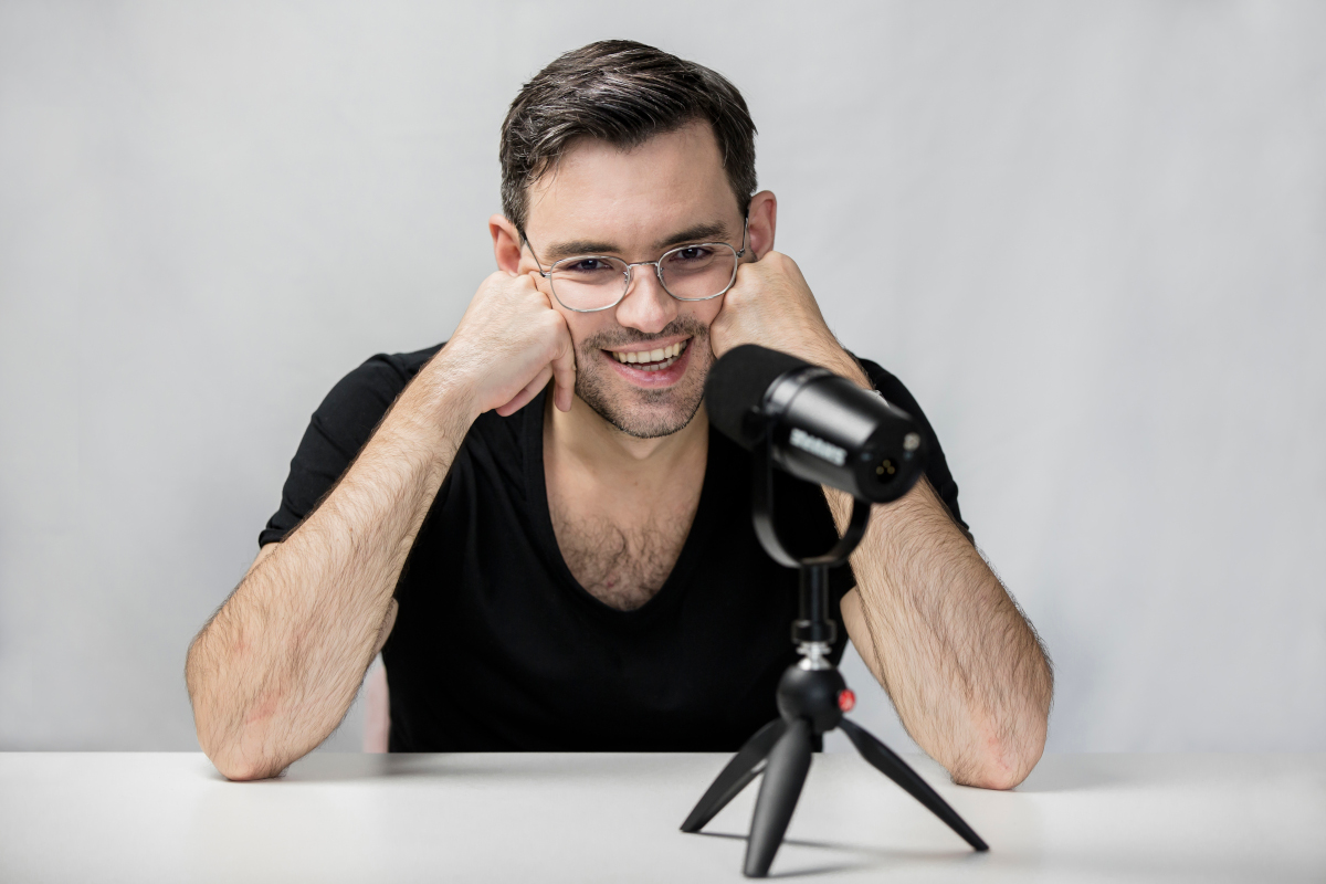 Wojciech Wawrzak, autor artykułu, siedzi uśmiechnięty przed mikrofonem.