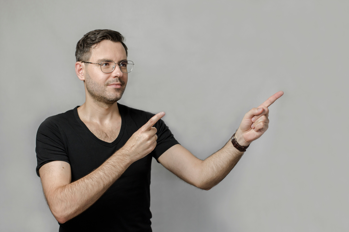 Wojciech Wawrzak, auto artykułu, pozuje z palcami wskazującymi w prawą stronę.
